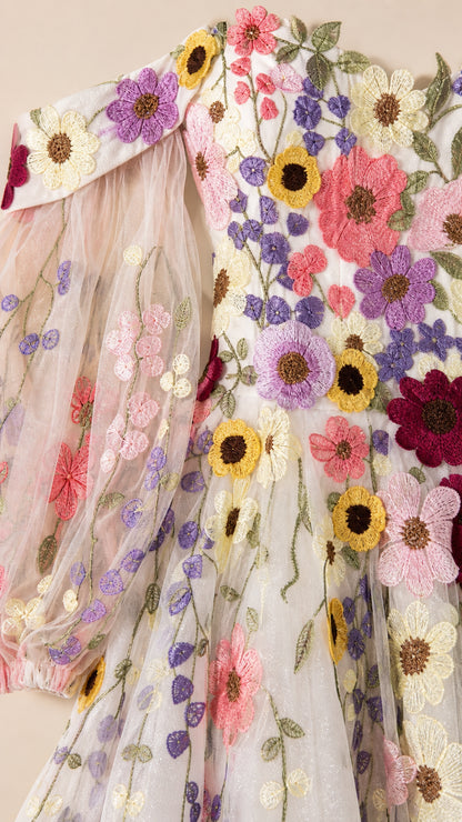 Close-up detail of vibrant 3D flower embroidery on sheer tulle fabric and sleeve