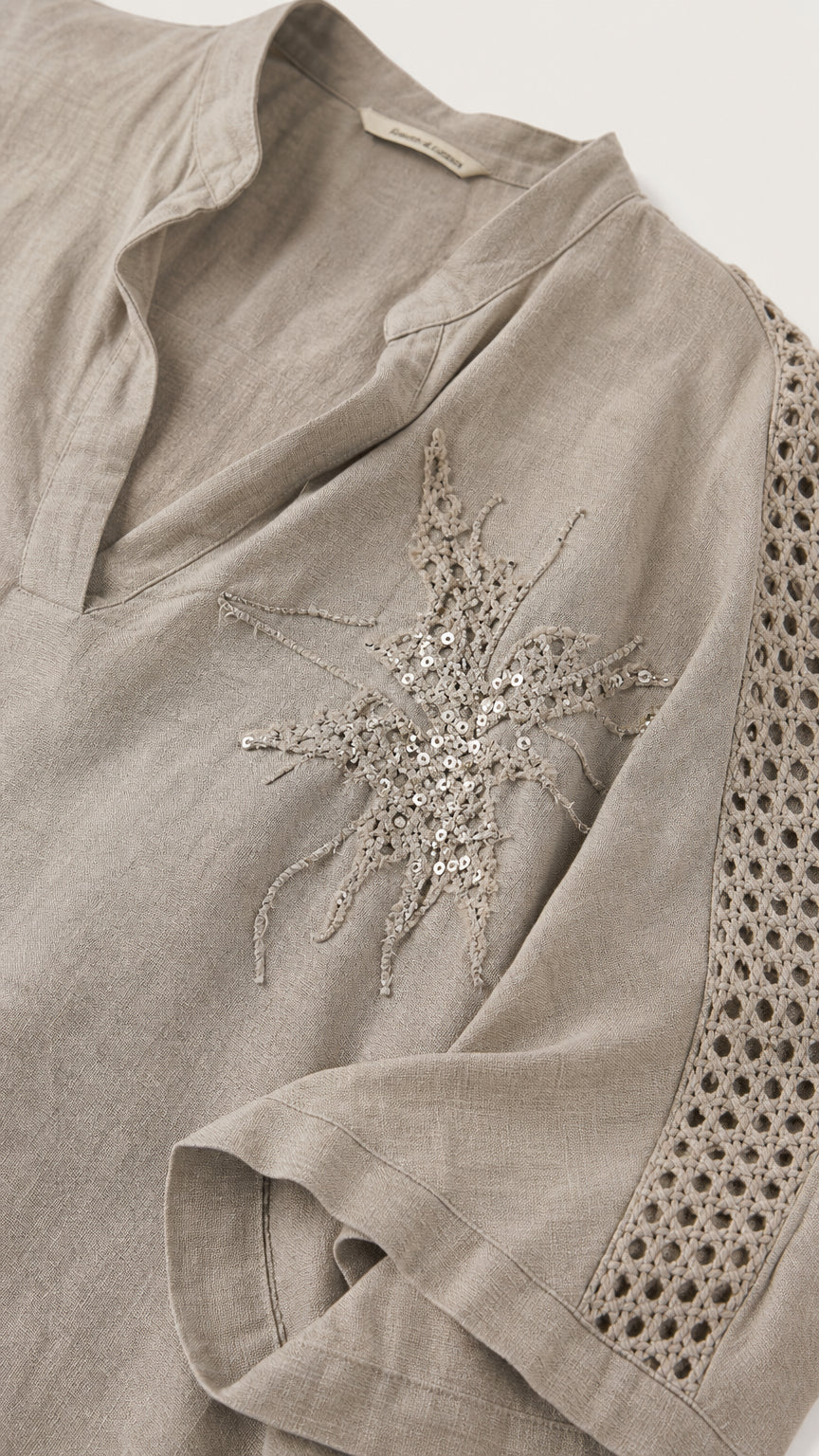 Close-up of taupe top showing V-neckline and sequin starburst embroidery