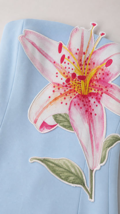 Close-up detail of pink and yellow lily floral print on light blue fabric