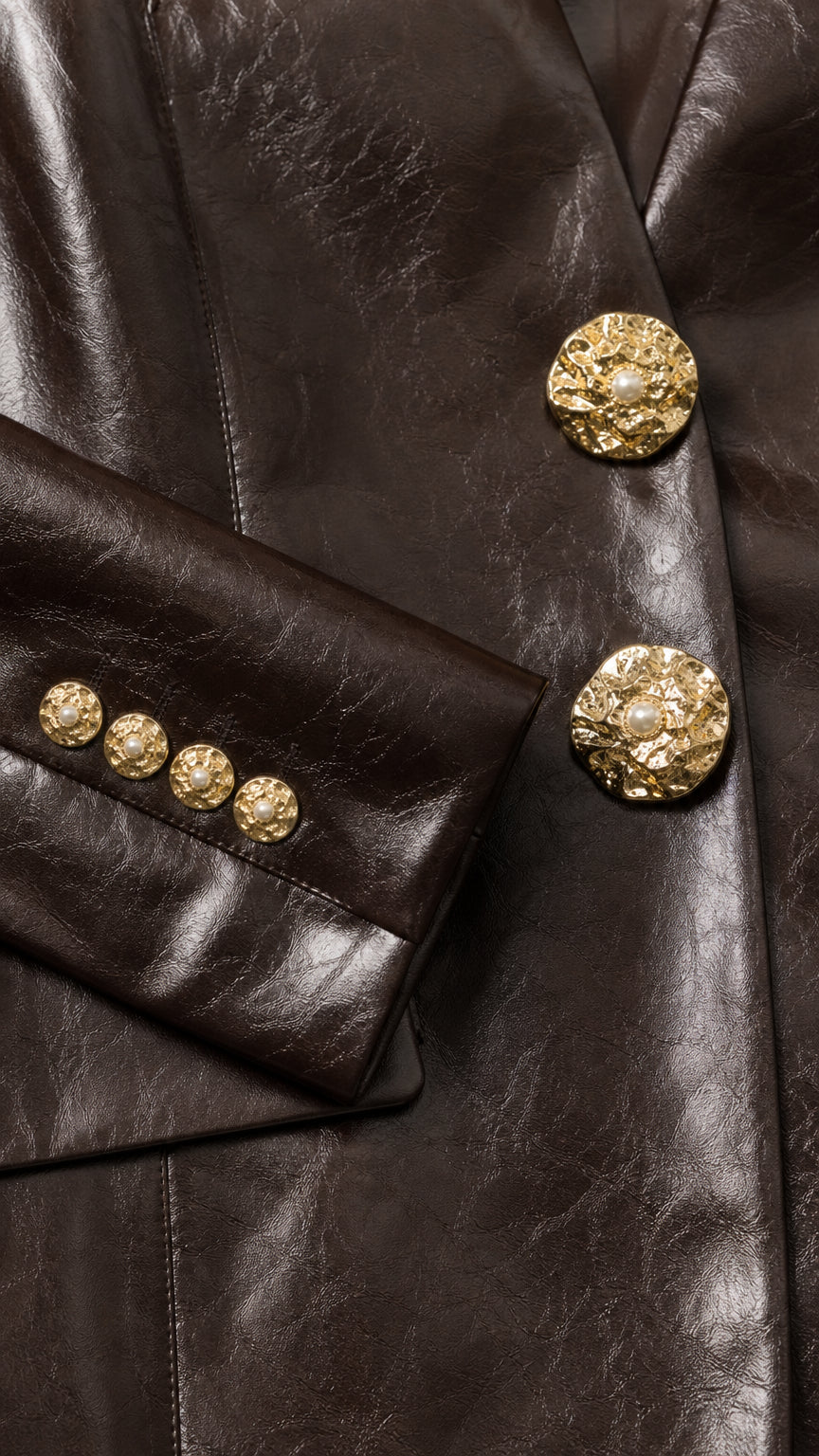 Close-up of gold-tone statement buttons and sleeve cuffs on dark brown blazer