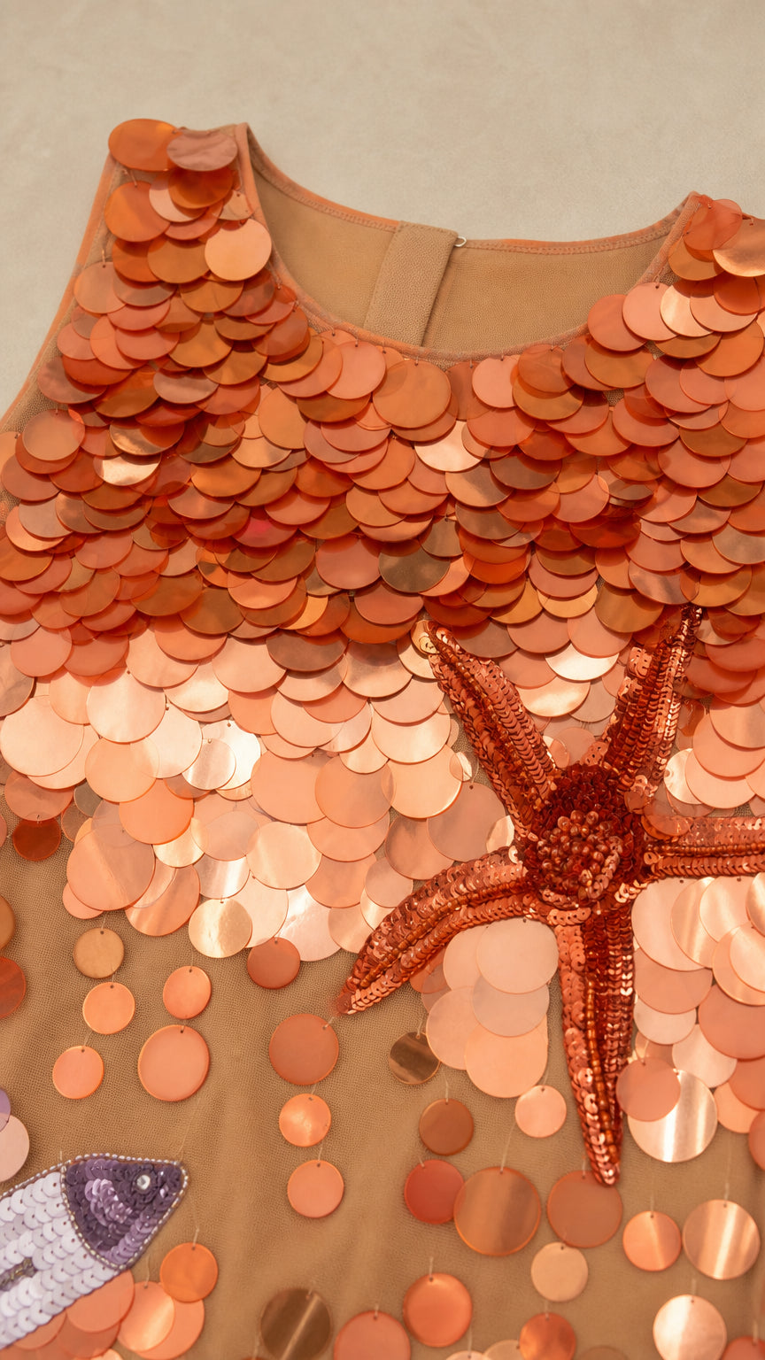Close-up detail of orange scale sequins and starfish applique