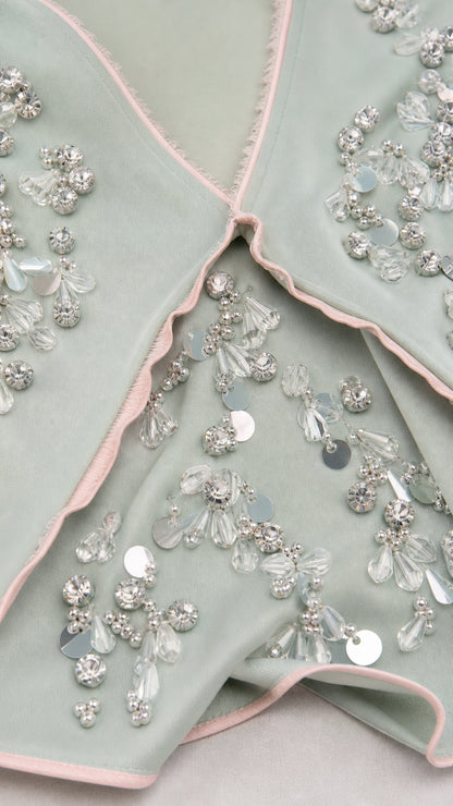 Close-up of beadwork and contrast piping details on sage green dress