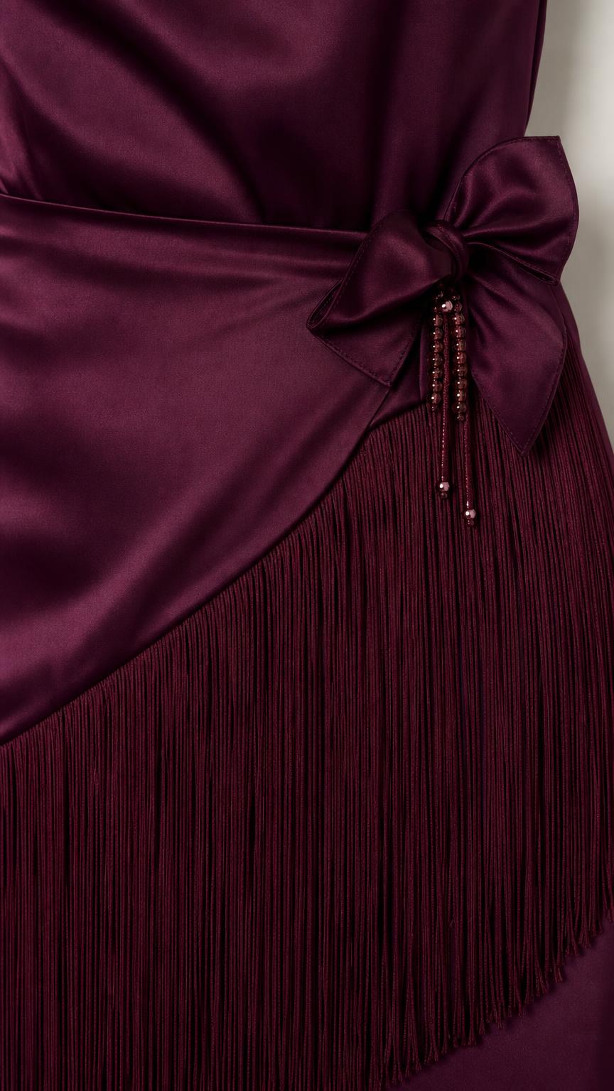 Close-up of waist bow detail and fringe hem on burgundy dress