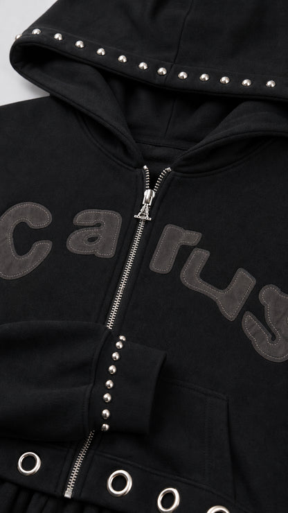 Close-up detail of black zip hoodie showing hood studs, sleeve studs, and hem grommets