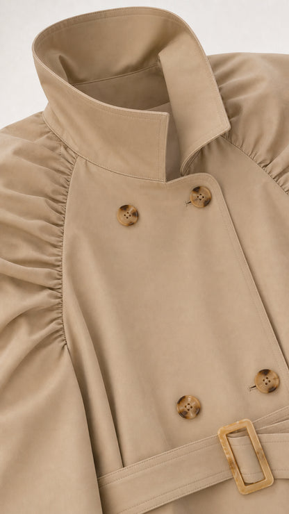 Close-up detail of beige trench coat lapel, tortoiseshell buttons, and gathered shoulder