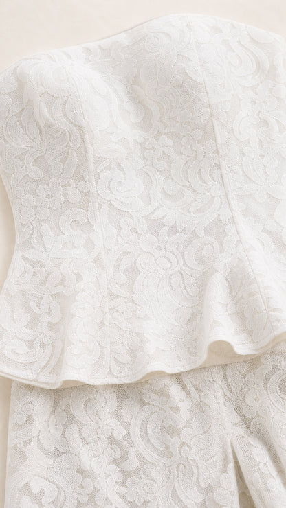 Close-up detail of white floral lace texture and peplum hem