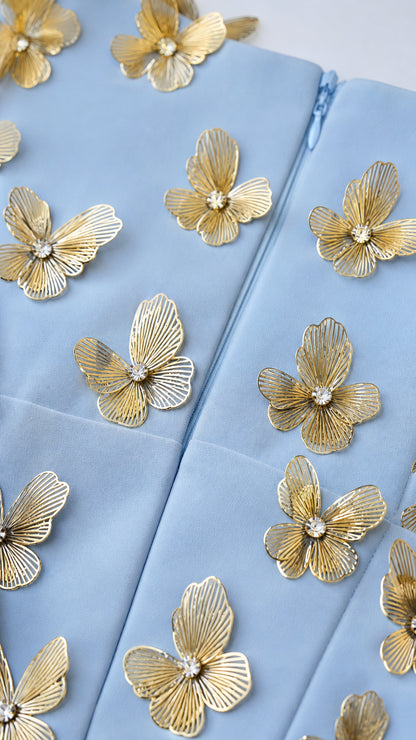 Close-up of gold butterfly appliques on light blue fabric