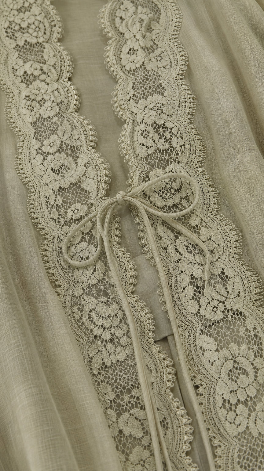 Close-up detail of floral lace placket and tie closure on sage green fabric