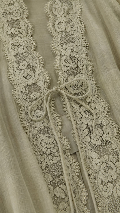 Close-up detail of floral lace placket and tie closure on sage green fabric