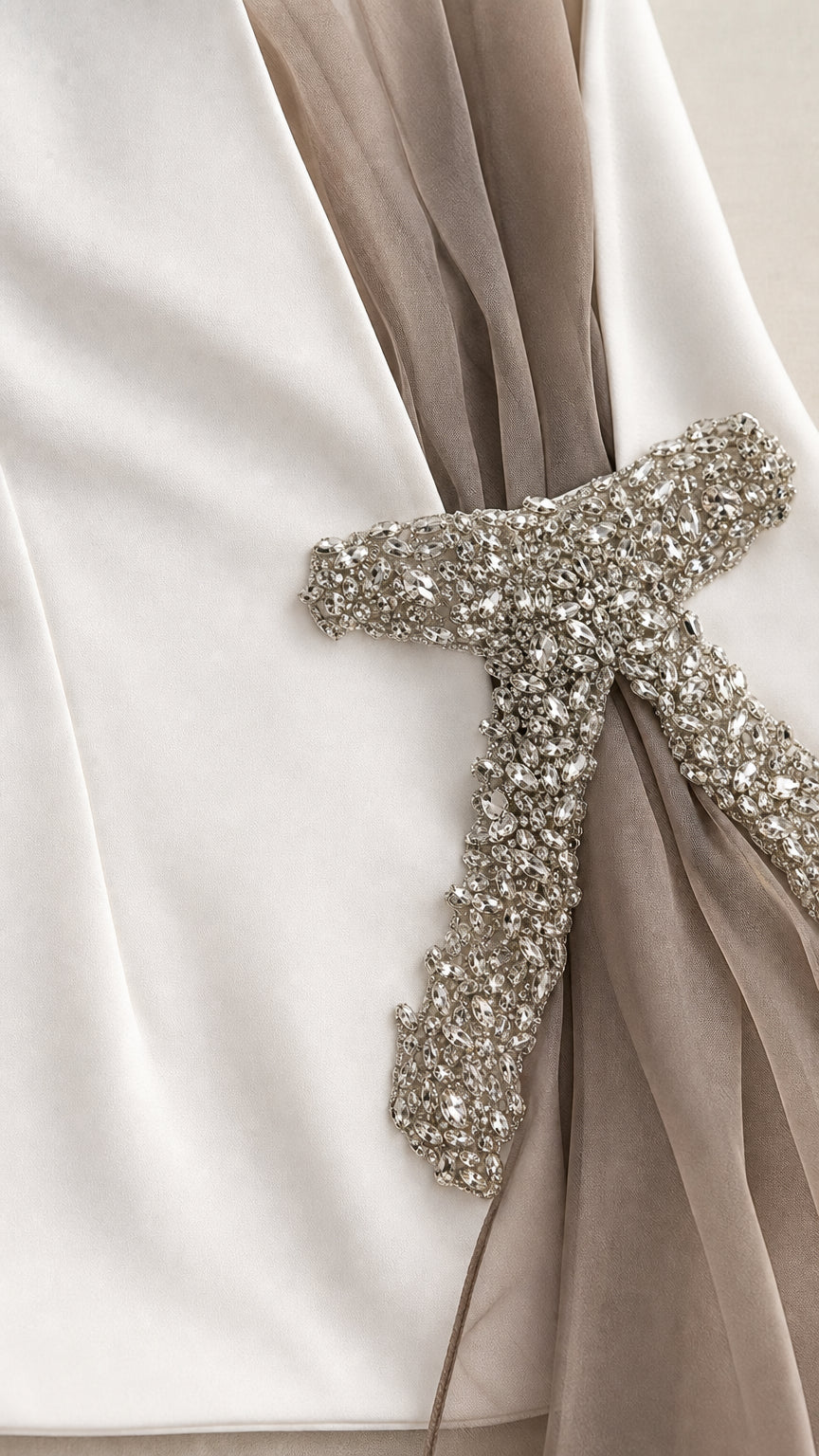 Close-up detail of crystal rhinestone buckle and sheer mesh overlay on white fabric