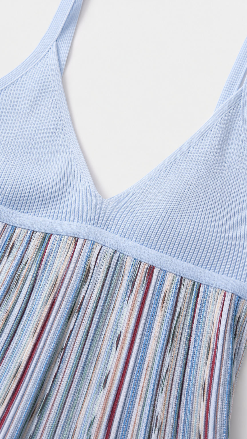 Close-up detail of light blue ribbed knit bodice and striped pleated skirt texture
