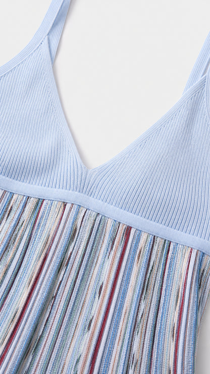 Close-up detail of light blue ribbed knit bodice and striped pleated skirt texture