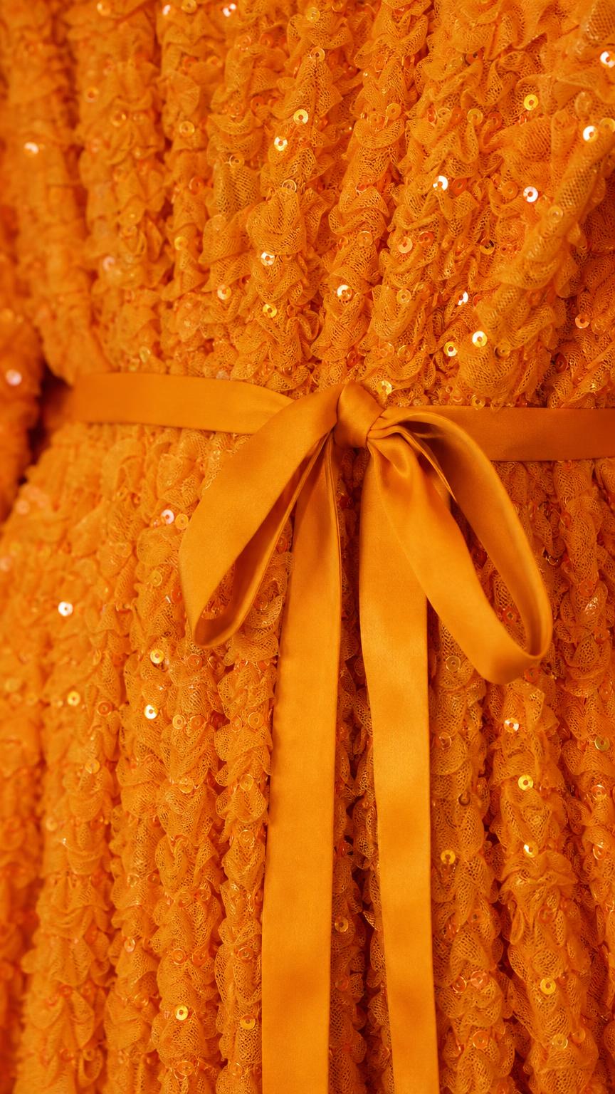 Close-up of waist tie and sequin texture on orange dress