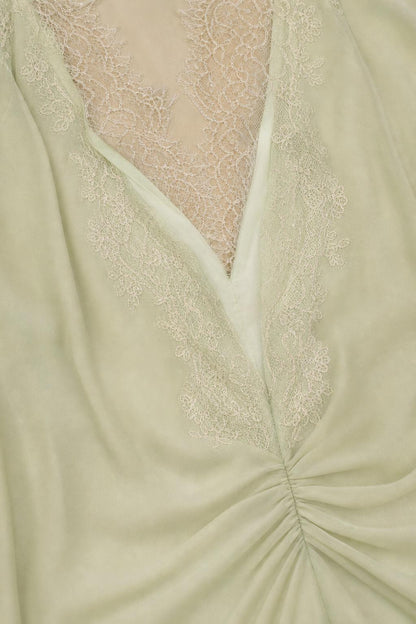 Close-up of V-neckline and lace trim detail in sage green