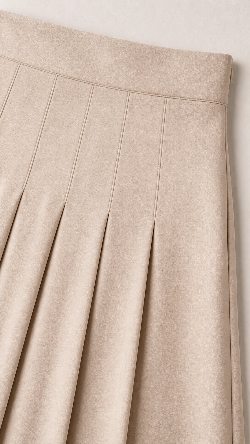 Close-up detail of beige skirt showing structured waistband and top-stitched pleats