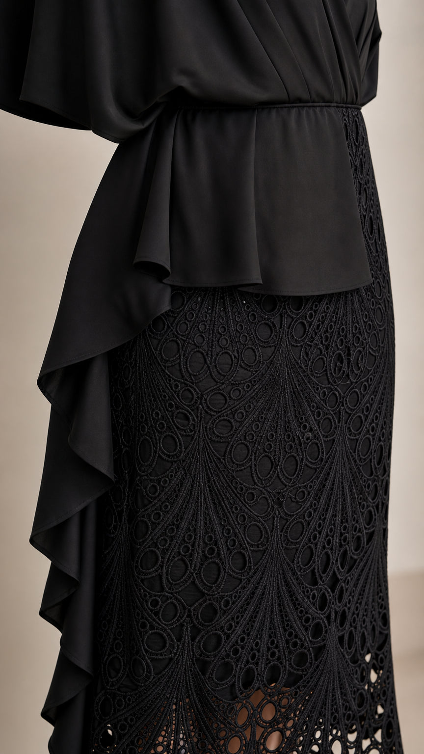 Close-up detail of black textured lace skirt and cascading drape ruffle