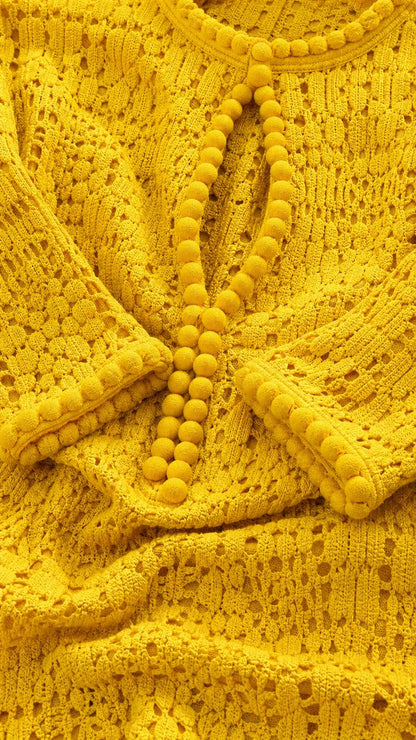Close-up detail of crochet knit texture and pom-pom buttons