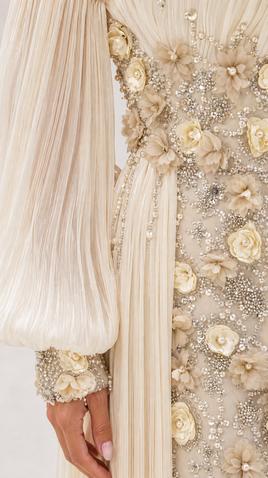 Close-up detail of champagne 3D floral appliqués, beadwork, and pleated sleeve cuff