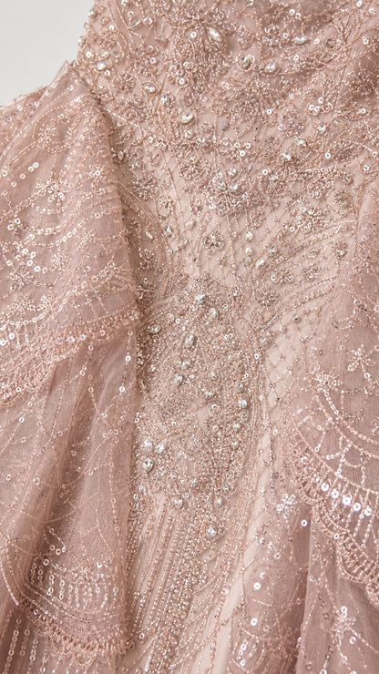Close-up detail of dusty rose intricate beadwork, sequins, and lace embroidery