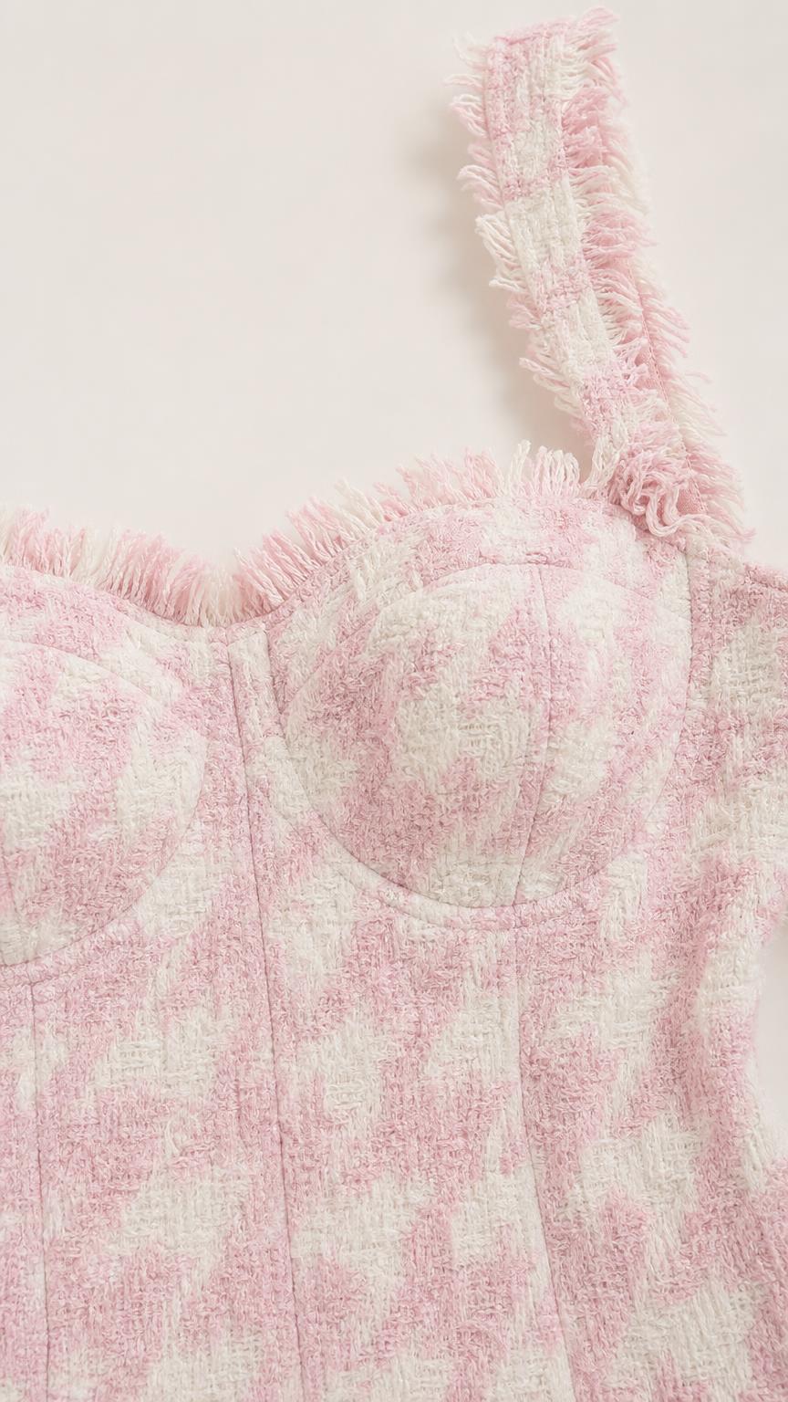 Close-up detail of textured pink tweed fabric, structured bustier, and frayed trim