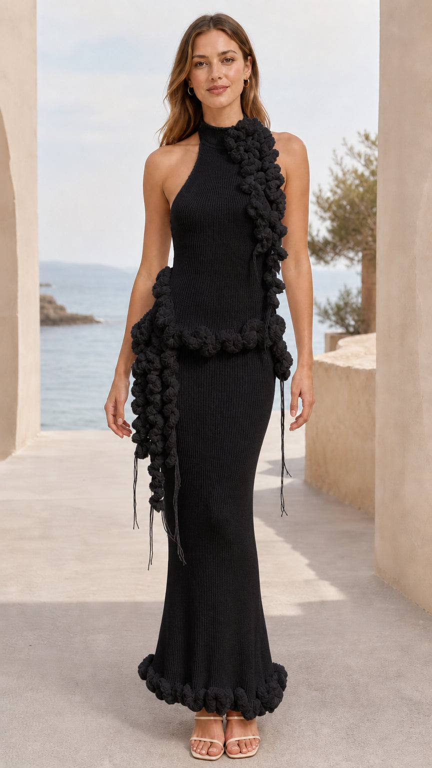 Full-length view of black halter neck ribbed knit maxi dress with black pom pom trim