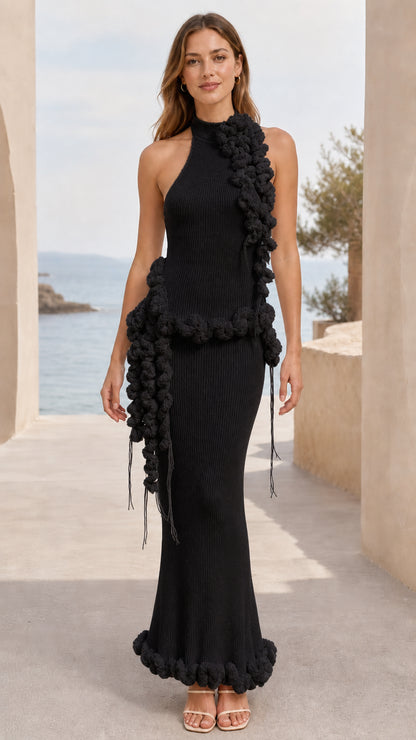 Full-length view of black halter neck ribbed knit maxi dress with black pom pom trim