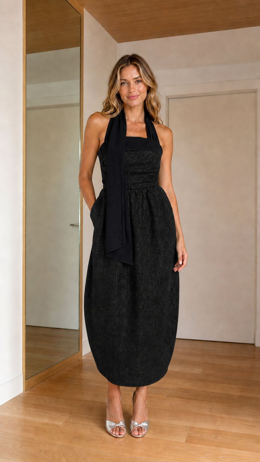 Front view of woman wearing all black halter tie cocoon midi dress