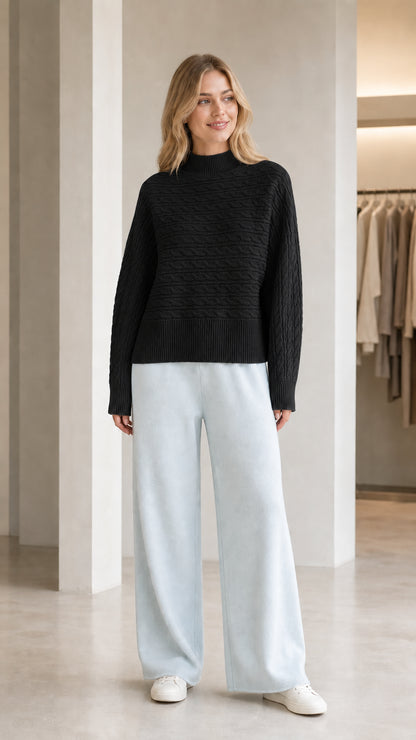 Model wearing black mock neck textured cable knit sweater with light blue pants