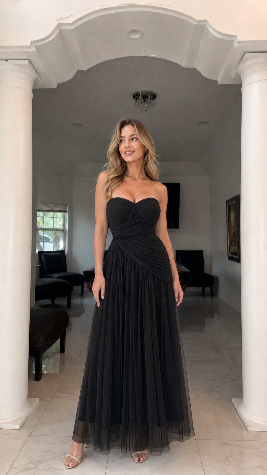 Front view of model wearing black strapless ruched tulle gown