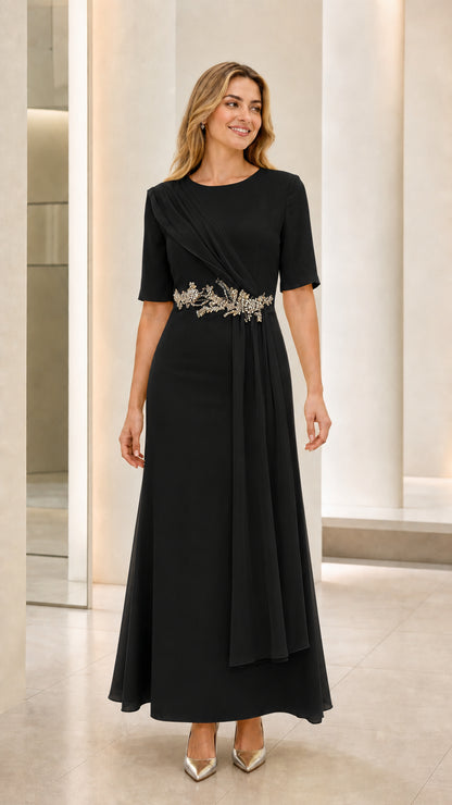 Front view of model wearing black short sleeve draped formal gown with crystal waist