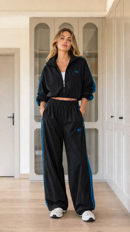 Model wearing black cropped tracksuit set with blue contrast side stripes