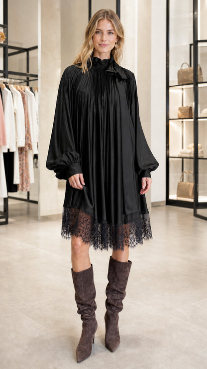 Model wearing black pleated satin dress with lace hem