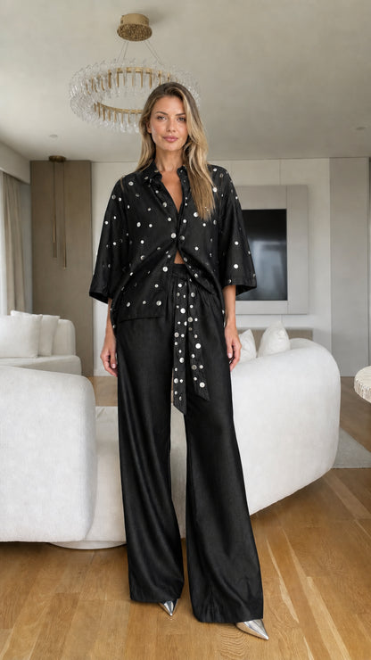 Model wearing black polka dot button-down shirt and matching wide-leg pants set