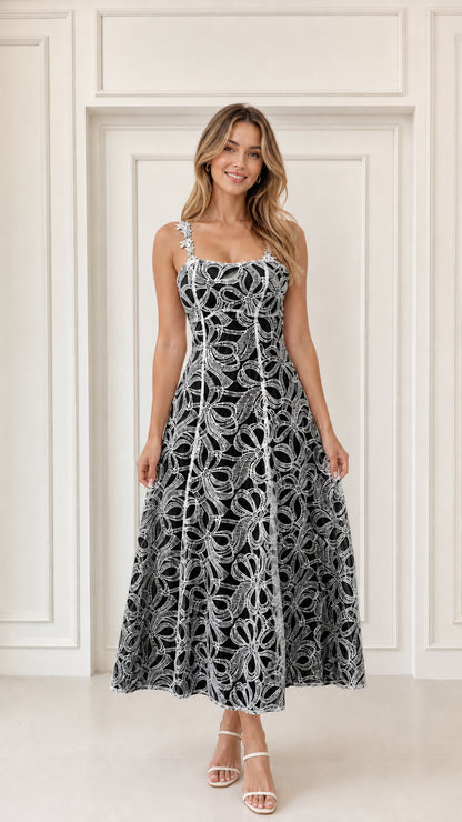 Woman wearing black embroidered floral lace A-line midi dress with white underlayer