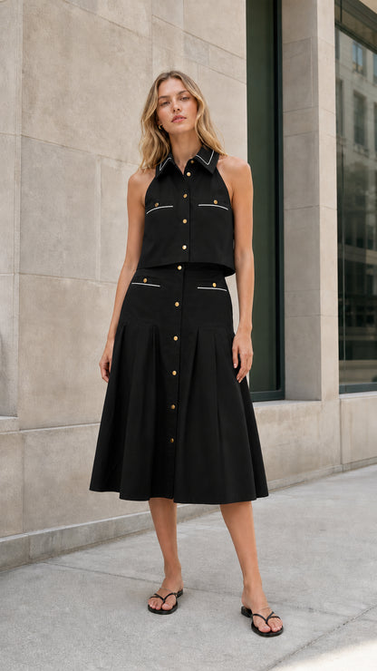 Black sleeveless collared top and pleated midi skirt set shown from the front