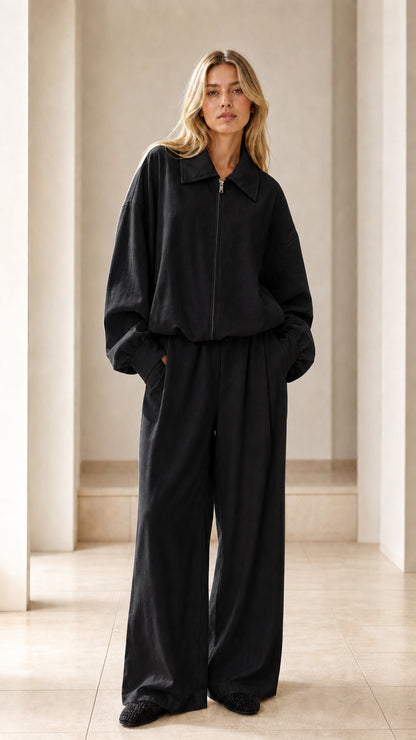 Front view of woman wearing black zip-up jacket and matching wide-leg trousers