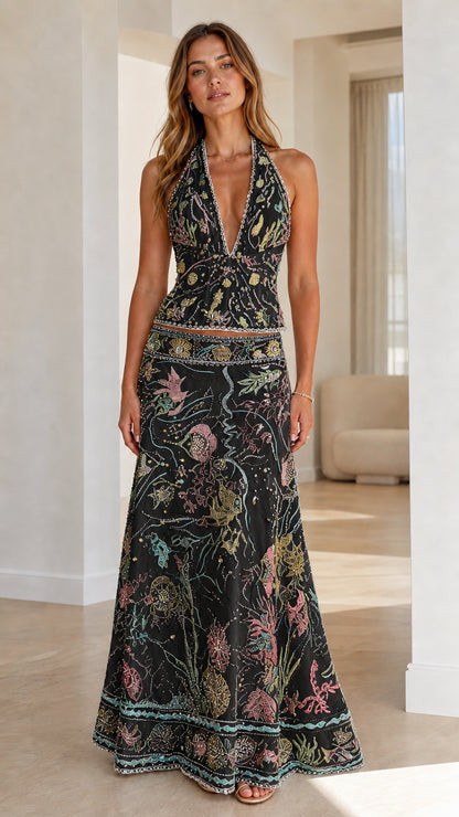Woman wearing black embroidered halter crop top and maxi skirt set