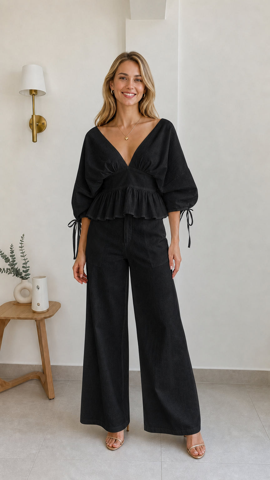 Model wearing black two-piece peplum and wide-leg pants set