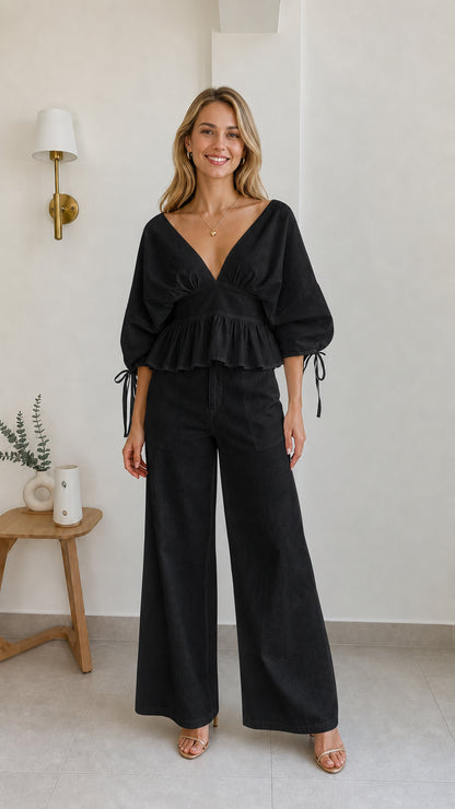 Model wearing black two-piece peplum and wide-leg pants set
