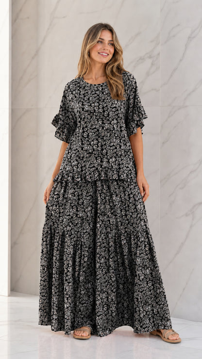Front full view of woman wearing Black floral ruffle sleeve top and tiered wide-leg pants set