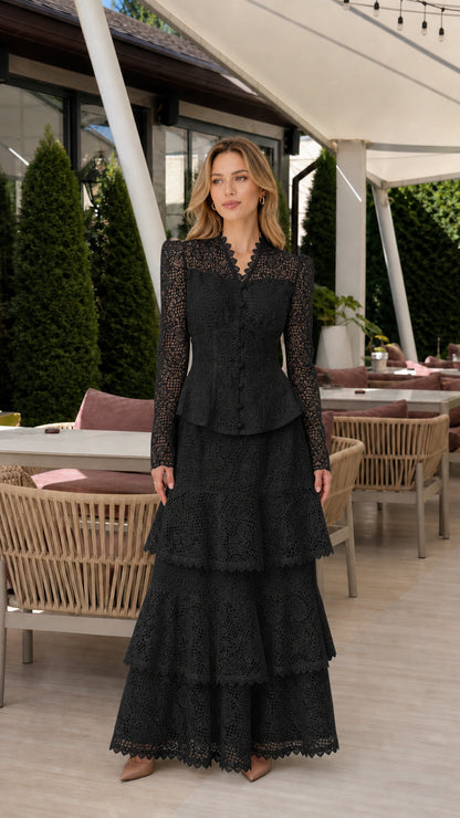 Front full view of woman wearing black long-sleeve lace peplum tiered maxi dress