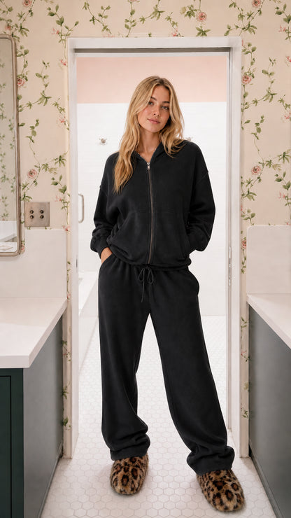 Model wearing black two-piece ribbed knit zip-up hoodie and wide-leg lounge pants set