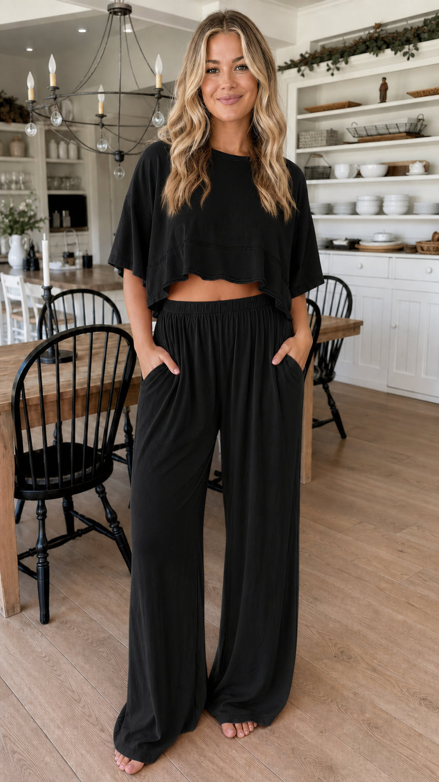 Front view of woman wearing black two piece cropped top and wide leg pant set