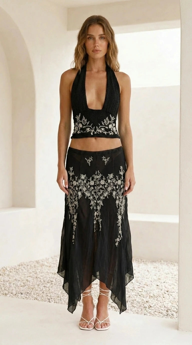 Model wearing black embroidered halter crop top and skirt set