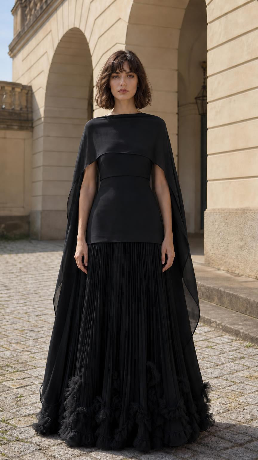 Front view of woman wearing black cape overlay pleated maxi dress