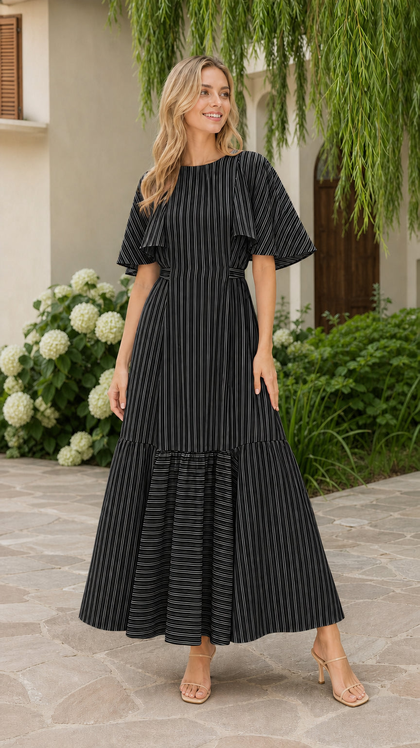 Front view of model wearing black striped flutter sleeve tiered maxi dress