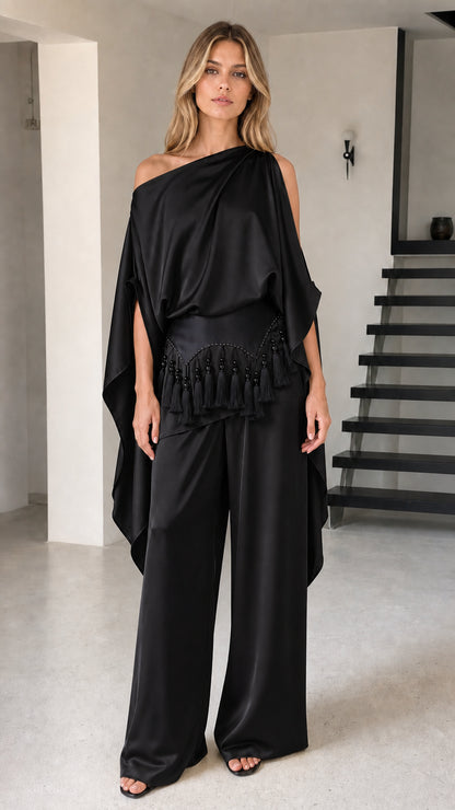 Model wearing black one-shoulder draped cape top and wide-leg pants set