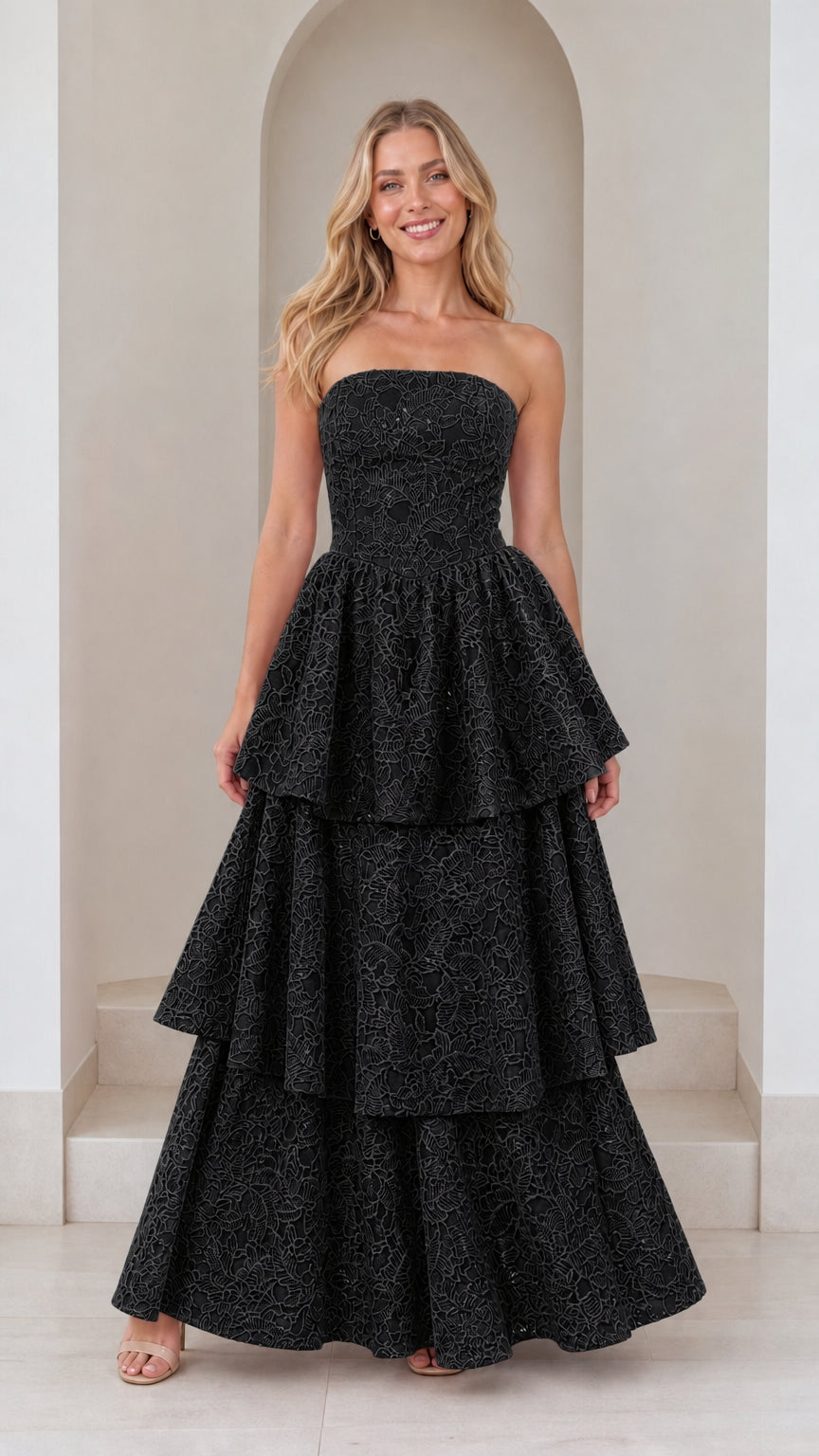 Front view of model in black strapless tiered maxi dress
