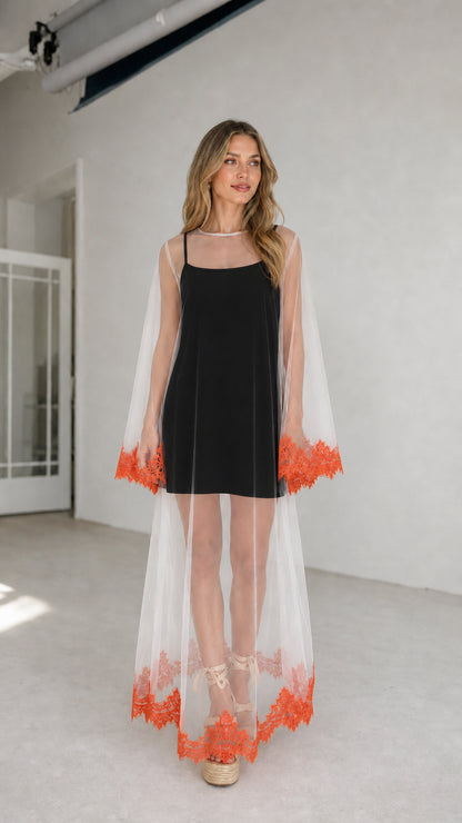 Model wearing black inner dress with white embroidered mesh duster