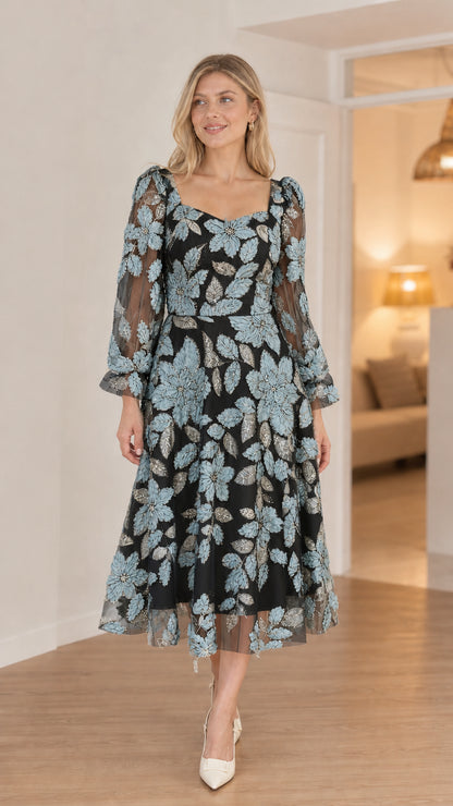 Front view of model in black floral applique midi dress